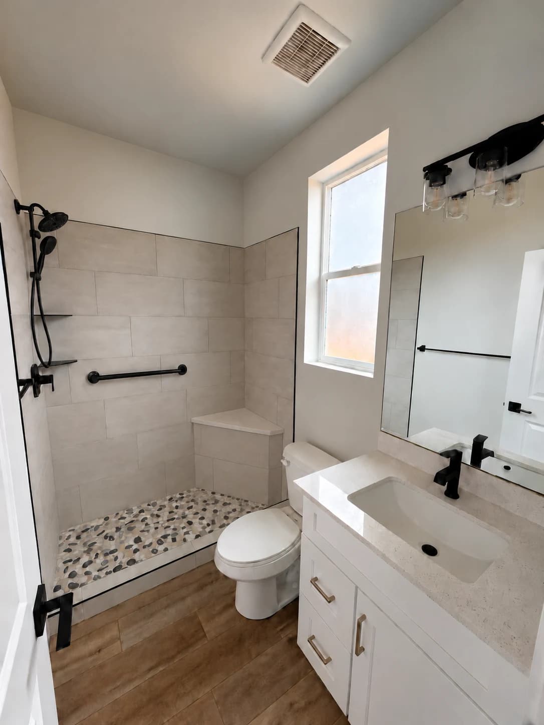 Shower illustration with a tiled corner bench, grab bar and overhead plus handheld shower fixture